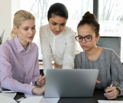 Focused multiracial female employees work on laptop together