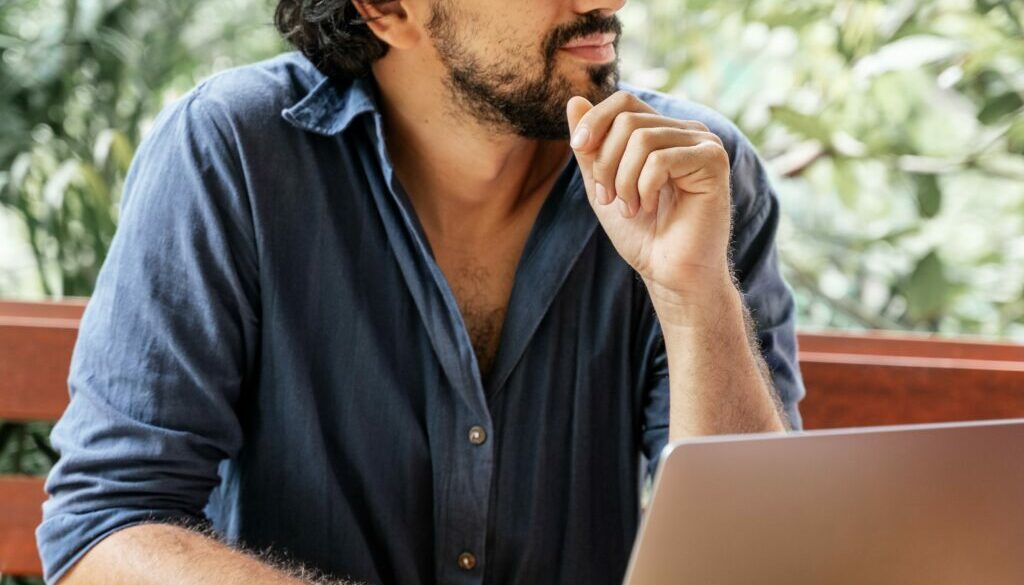 Handsome young curly latin man with glasses working on a laptop